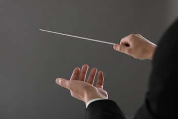 Conductor with baton on grey background, closeup