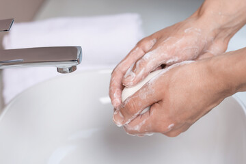 Woman washing her hands with soap above sink in bathroom, closeup