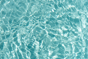 Blue water with ripples on the surface. Defocus blurred transparent blue colored clear calm water surface texture with splashes and bubbles. Water waves with shining pattern texture background.