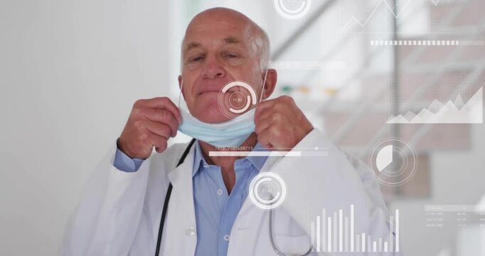 Male medical doctor pulling down surgical mask indoors, showing floating graphs and circle icons