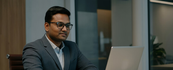 Asian male young professional in modern office working on laptop