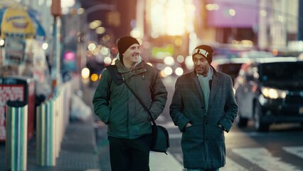 Two men walking together in Manhattan, New York, are enjoying a conversation during sunset