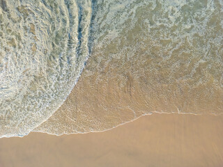 Aerial view of big waves lapping the sandy beach