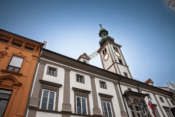 Low‑angle view of Ljubljana’s baroque City Hall (Mestna hisa, or rotov) and green‑domed clock tower rising above the old‑town square, captured on a clear evening in Slovenia capital.