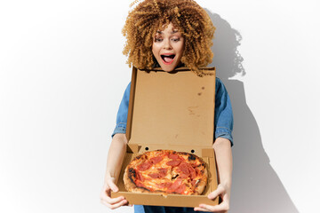 Young woman with curly hair joyfully holding a pizza box, showcasing excitement and happiness with vibrant colors, perfect for food lovers and pizza promotions