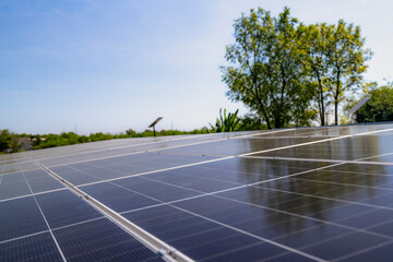 Close up view of solar panels installed on a carport with trees and parked cars under a clear blue...