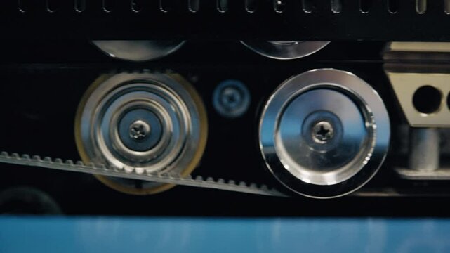 A smooth pan right reveals a spinning conveyor belt alongside interlocking gears, highlighting precise motion in a factory environment