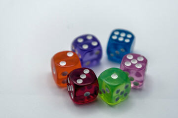 Colorful translucent dice in various colors on a light surface
