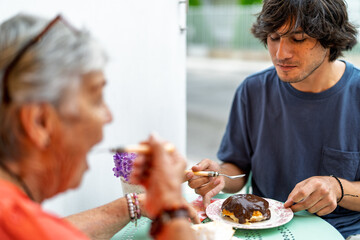 Grandson and grandmother enjoying lunch together at outdoor cafe