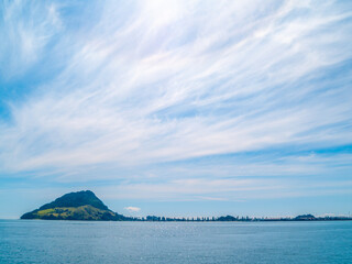 View across Tauranga harbour to landmark Mount Maunganui on horizon with white converging cloud pattern.