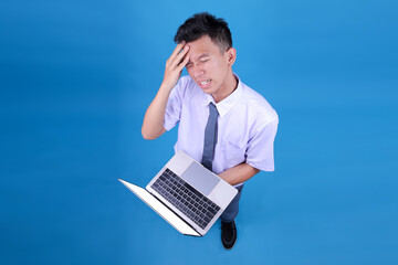 Stressed Asian Student Holding Head and Feeling Demotivated While Working on Laptop