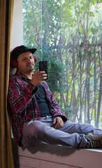 man sitting by the window listening to music