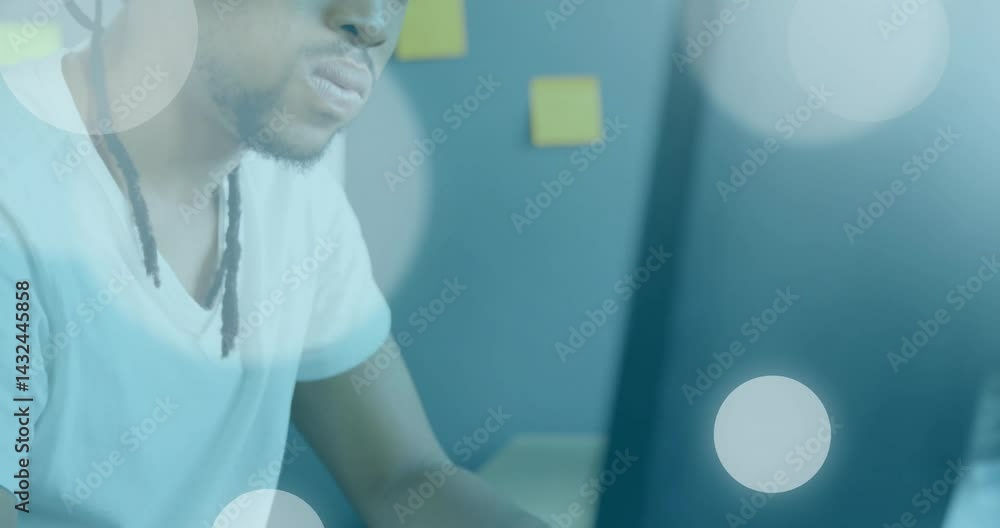 Poster man reviewing design ideas on monitor in tech workspace, floating chart icons and sticky notes