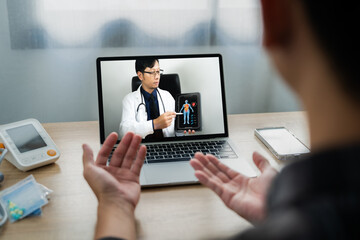 Male patient talking on video call with doctor, virtual therapist consults young man during online appointment on laptop at home Online video conferencing of doctors via telemedicine 