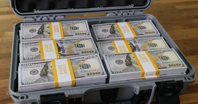 Filling case with dollar bill packs on wooden table in office. Safe cash money transportation to bank concept. Financial success of business