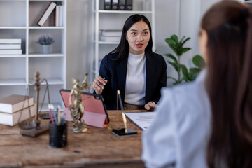 Two lawyers in suits discussing legal matters at a desk with a gavel, scales of justice, and a law book, symbolizing law and justice, justice and lawyer Business partnership meeting concept.
