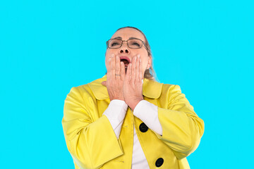 Woman in yellow coat expressing surprise in front of bright blue background while showcasing...