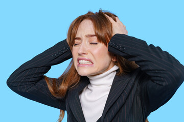 Woman expressing stress with hands in hair against blue background during a tense moment at work