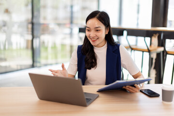 Obraz premium asian business woman sit at laptop holding papers, read received contract, agreement, legal documents smile feel satisfied, got good news. Loan repayment, career advance, success concept 