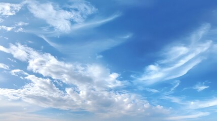 Obraz premium Bright blue sky with soft, wispy white clouds on a sunny day