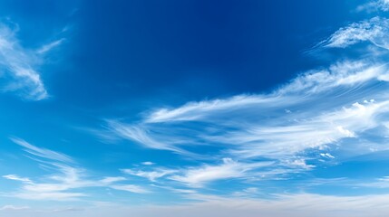 Obraz premium Crystal clear blue sky with soft, wispy white clouds on a peaceful day