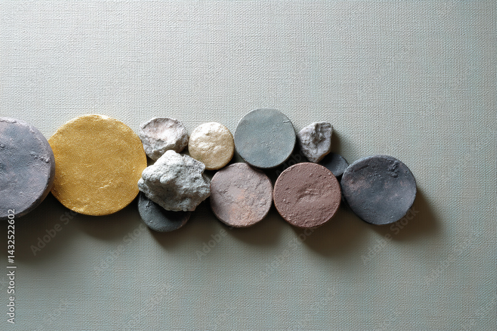 Poster Artistic arrangement of metallic mineral elements on textured surface, featuring circular and irregular shapes in various colors