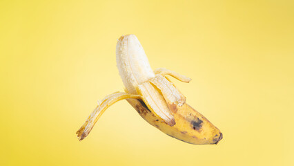 Half peeled banana yellow background with copy space