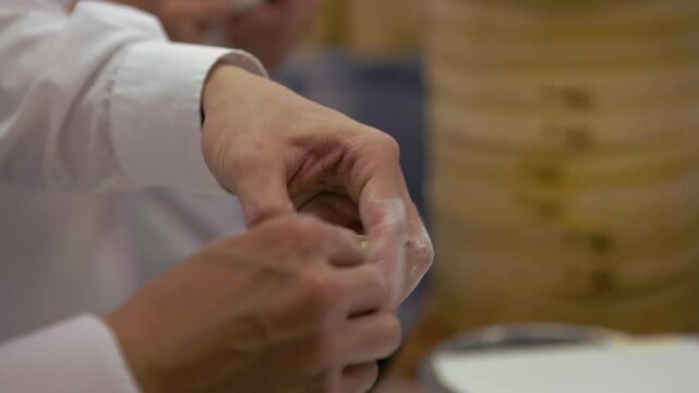 A team of Taiwanese chefs expertly prepares traditional dumplings, their hands skillfully shaping the dough. In a bustling restaurant, the chefs creating fresh and authentic flavors.