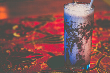 blueberry aryan in a glass with a straw on a table