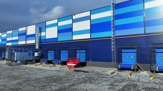 View from drone camera of big colorful industrial building. Contemporary logistics hub outdoors. Nice blue and white colors of warehouse. Storage industry building. Factory area
