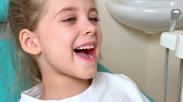 Little girl sitting in dentist chair showing her teeth to doctor. Baby teeth concept. Beautiful smiling preschool girl lost baby tooth. Dental hygiene concept