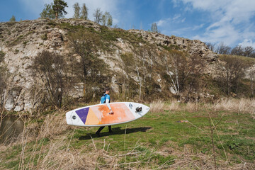 An adventurous paddleboarder heads to the waters edge, beginning a journey through a stunning...