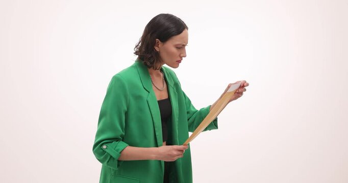 Woman takes out document from envelope with serious and shocked expression. Worker in green blazer carefully examines and reads important paper