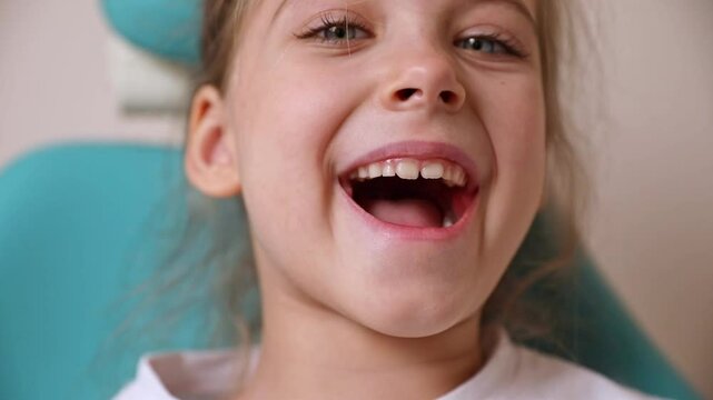 Little girl sitting in dentist chair showing her teeth to doctor. Baby teeth concept. Beautiful smiling preschool girl lost baby tooth. Dental hygiene concept