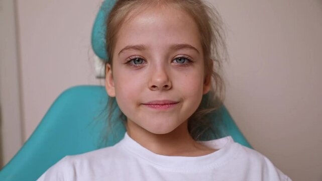 Beautiful white healthy baby teeth. Happy little girl sitting in dentist chair and smiling. Milk teeth close-up. Slow motion footage