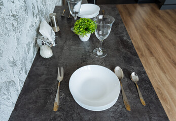 There is a beautifully arranged table featuring plates, silverware, glasses, and a lovely plant placed on it, creating an inviting and warm atmosphere for dining or serving meals