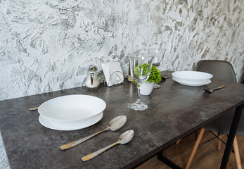 A beautifully set dining table adorned with dishes, utensils, glasses, and a lovely plant arrangement placed on it, creating an inviting atmosphere for meals and gatherings