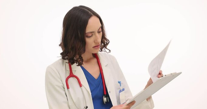 Concentrated woman doctor studies test results of patient against white background. Physician holds laboratory report on clipboard. Slow motion