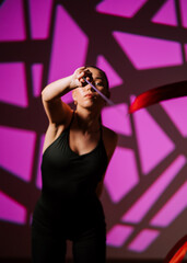 Woman performs rhythmic gymnastics with ribbon during indoor practice session