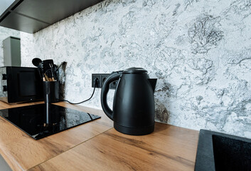 The sleek black kettle elegantly sits on the warm wooden counter, enhancing the cozy kitchen...