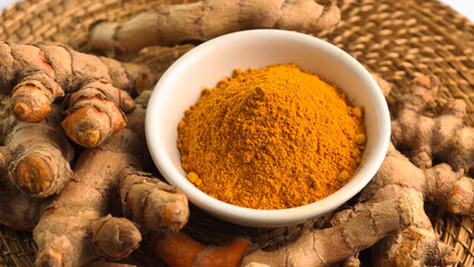 Turmeric powder in a cup and fresh turmeric