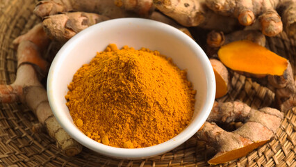 Turmeric powder in a cup and fresh turmeric