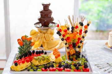 Colorful Display of Fruit Skewers With Chocolate Fountain on Wedding Table
