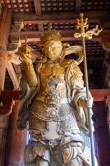 Majestic guardian deity standing tall inside a historic Japanese temple, showcasing intricate craftsmanship and serene expression