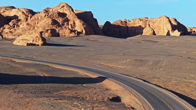 Asphalt road winding through the spectacular yardang landform desert in Xinjiang, China.