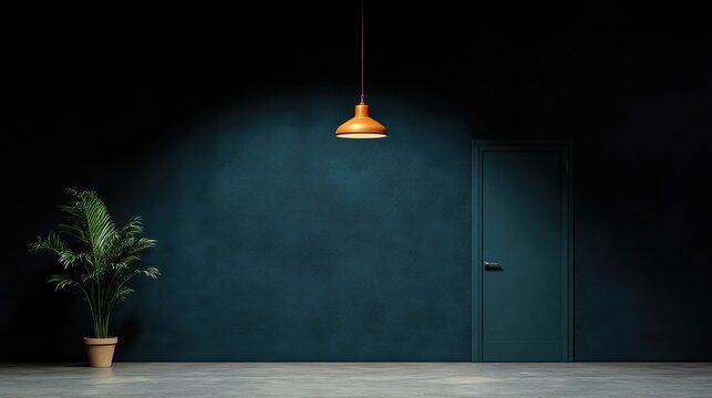 Pendant lamp casts a warm spotlight on a dark teal wall in a minimalist room with a potted plant and closed door.