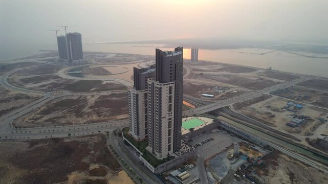 Aerial reveal of the Black and Champagne Pearl Towers in Lagos, Nigeria, showing the geometric growth of Eko Atlantic&rsquo;s smart city canal network and coastal expansion.