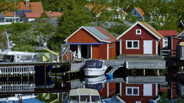 Pan shot of harbor with boats and red houses during the day in Koster Islands, Bohuslan, Sweden, establishing shot