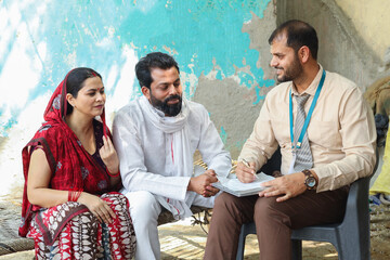 Indian bank person or insurance agent with farmer couple discussing scheme of loan. Banking and...