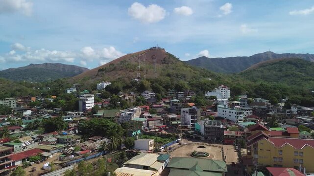 Coron town rooftops and streets spread below Mount Tapyas in Palawan with sunny hills local buildings and a broad mountain backdrop
